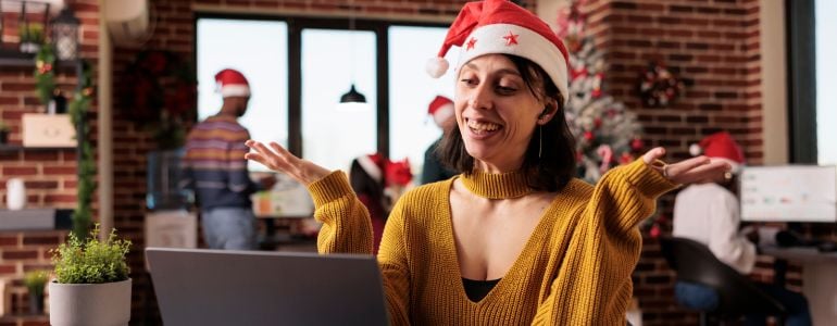 Mujer feliz en su trabajo con gorro navideño después de regalar conocimiento en Navidad
